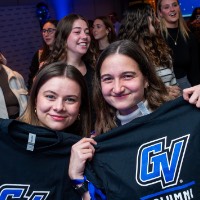 Two friends holding up GV Alumni t-shirt